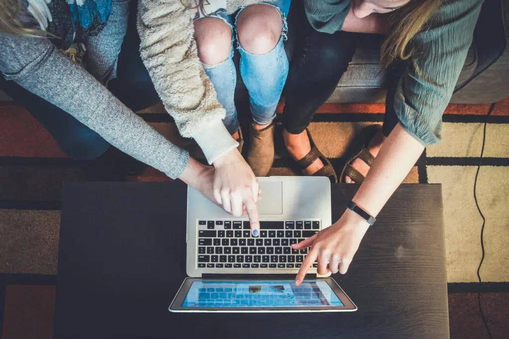 Three people pointing at a computer screen.